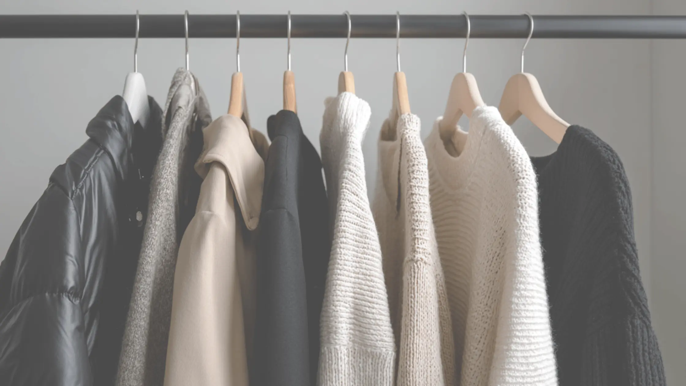 neutral clothing hanging on a rack representing a minimalist wardrobe