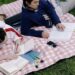 image of two people laying on a blanket int he grass reading