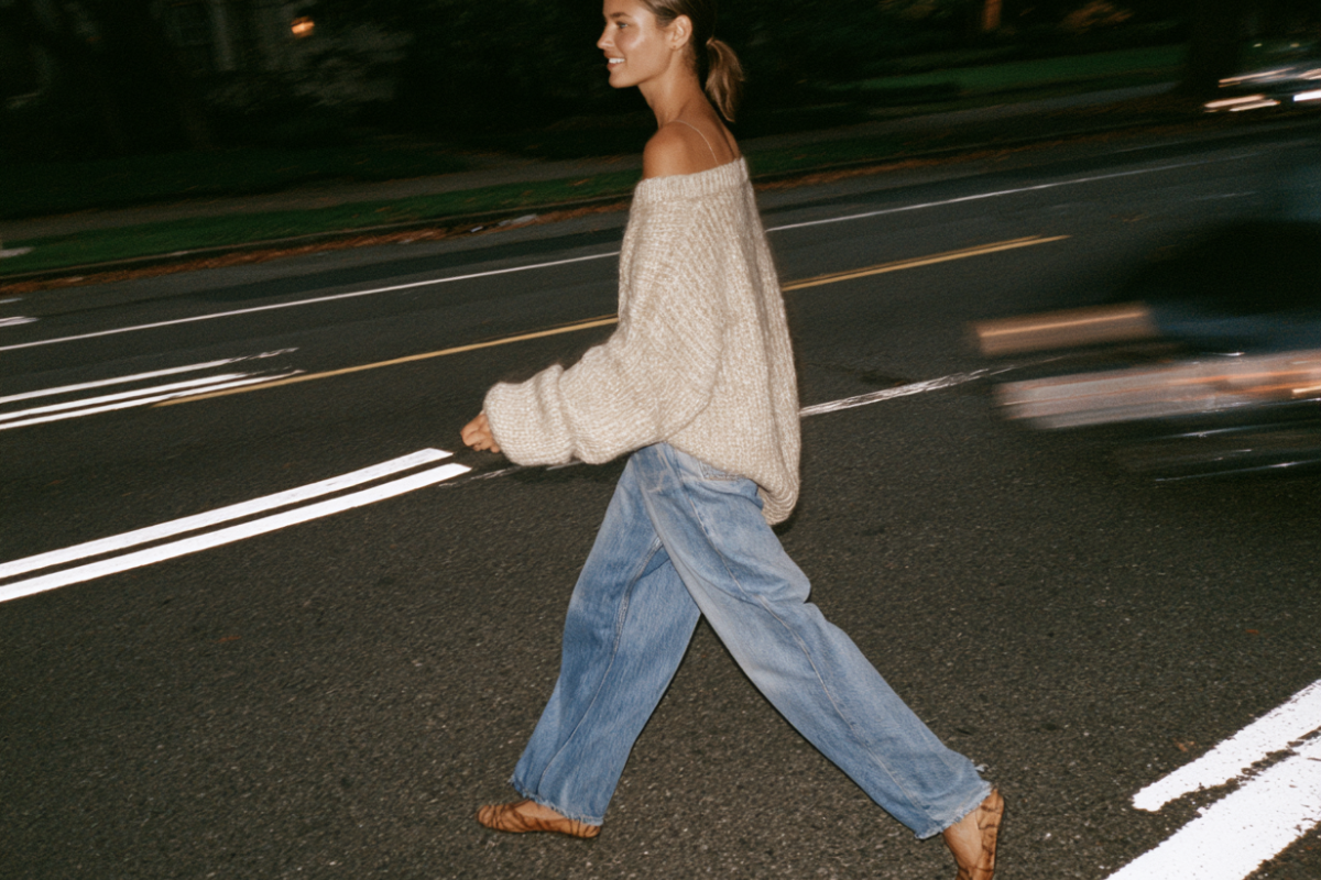 woman walking across street in cozy fall out fit - oversized sweater, baggy jeans and flats