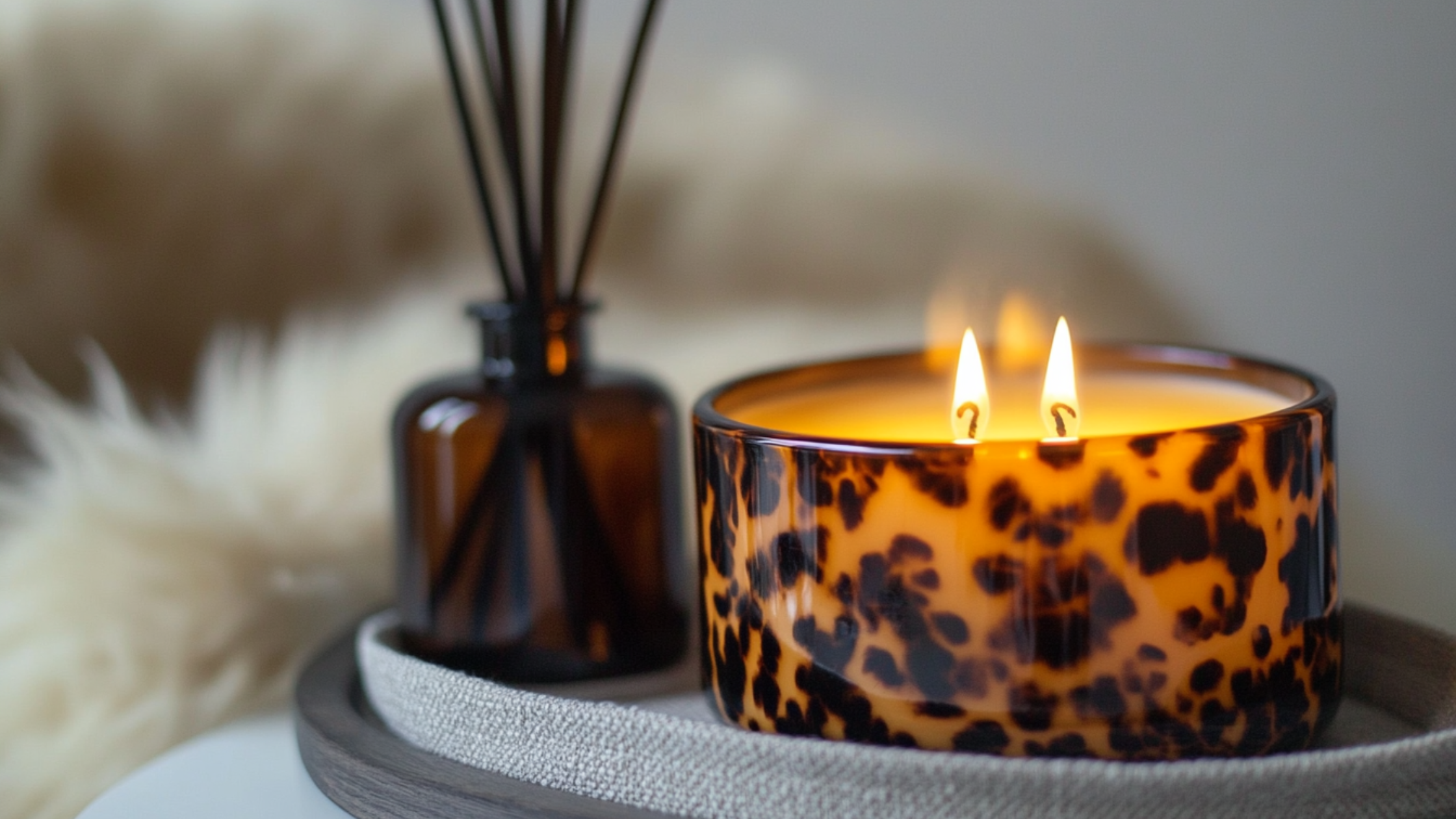 fall candle sitting on coffee table on tray with diffuser. fluffy blanket in the background